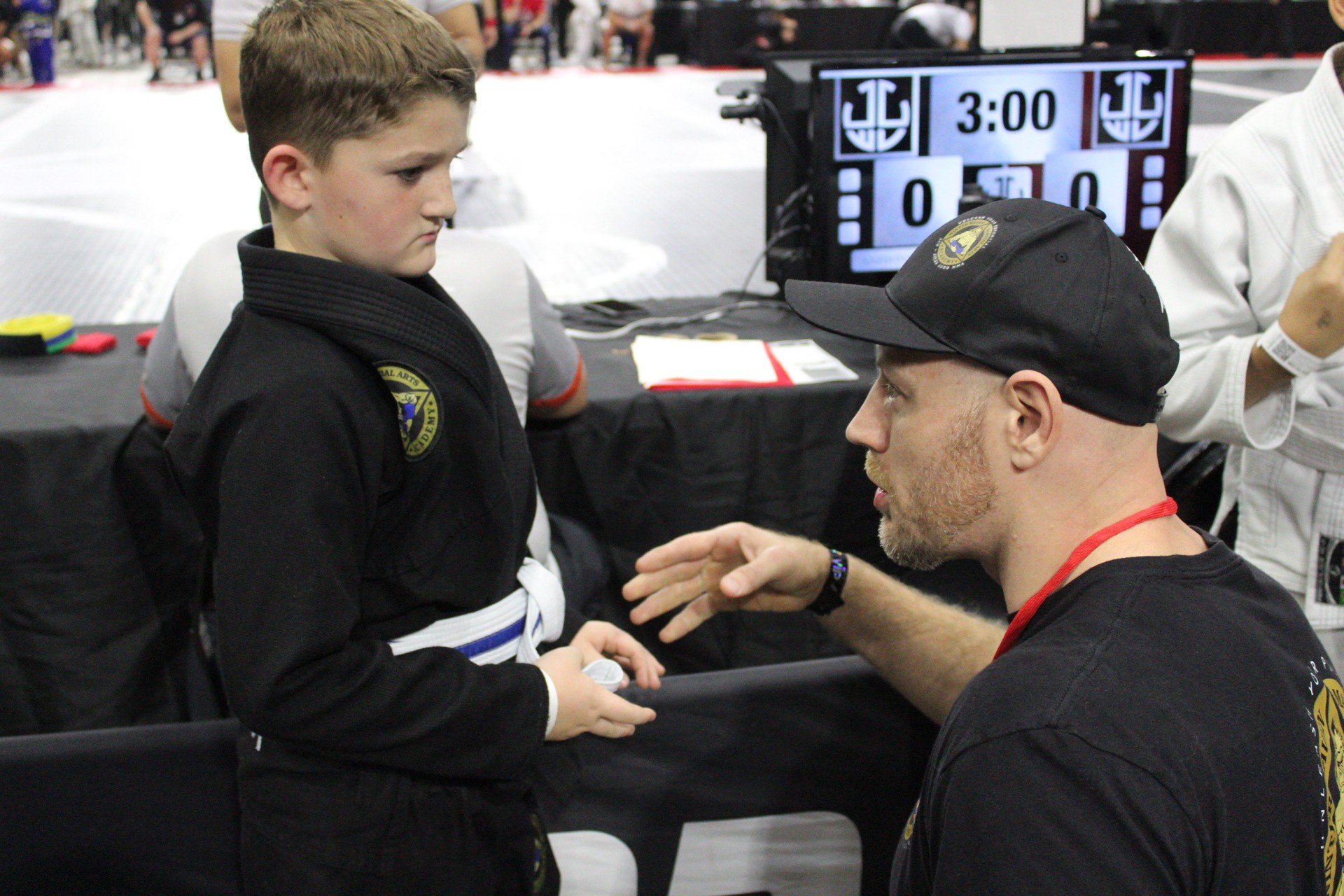 Coach giving last-minute advice to a young competitor before his jiu-jitsu match