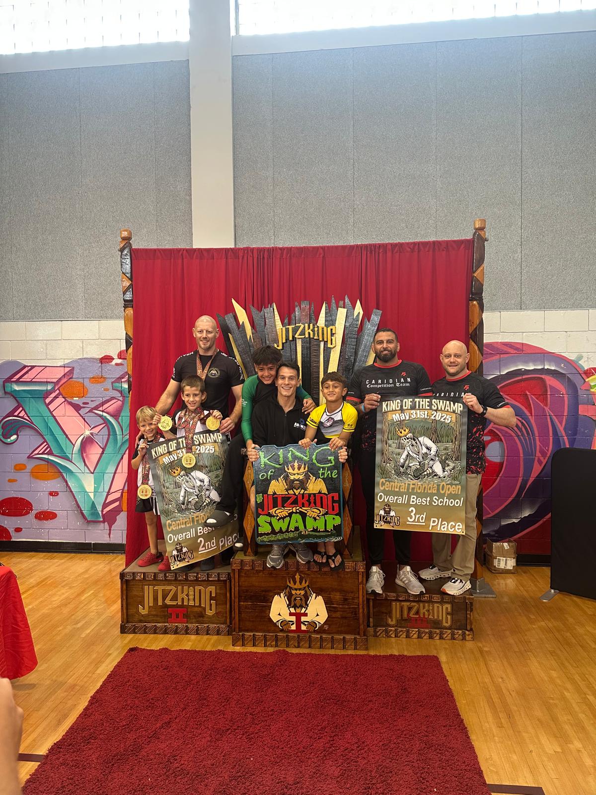 Winter Haven Martial Arts Academy coaches and kids on the King of the Swamp podium holding second place team banners